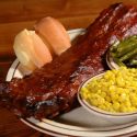 Plate with a rack of ribs, roll, corn, and green beans