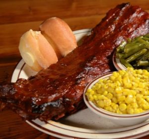 Plate with a rack of ribs, roll, corn, and green beans